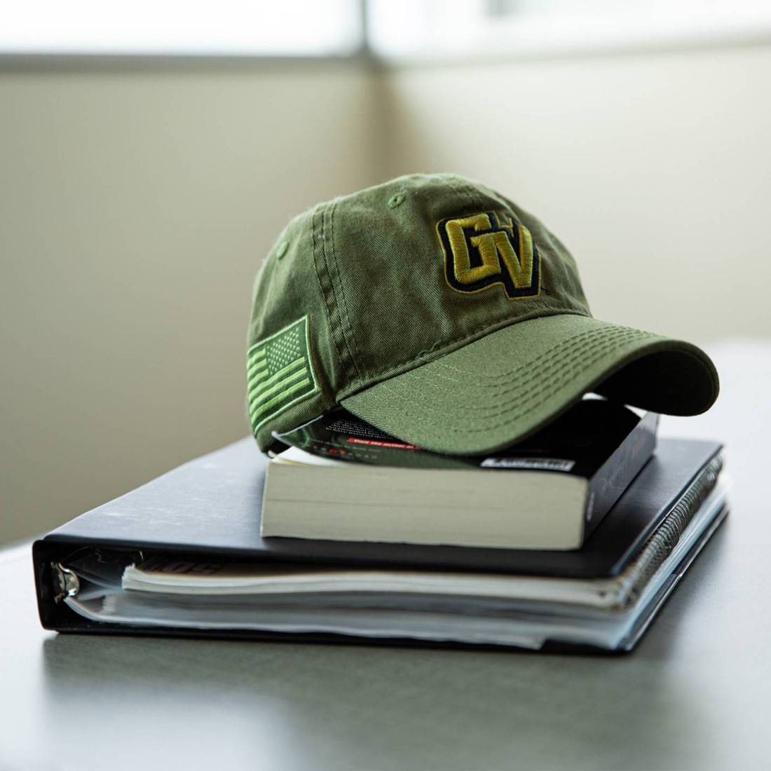 Green GV Vet hat on top of books